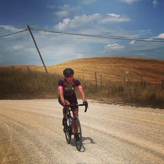 Anke op de racefiets over een karakteristieke witte Strade Bianche in Toscane