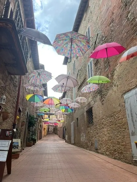Kleurrijke paraplu's boven een straatje in het historische dorp Paciano in Umbrië