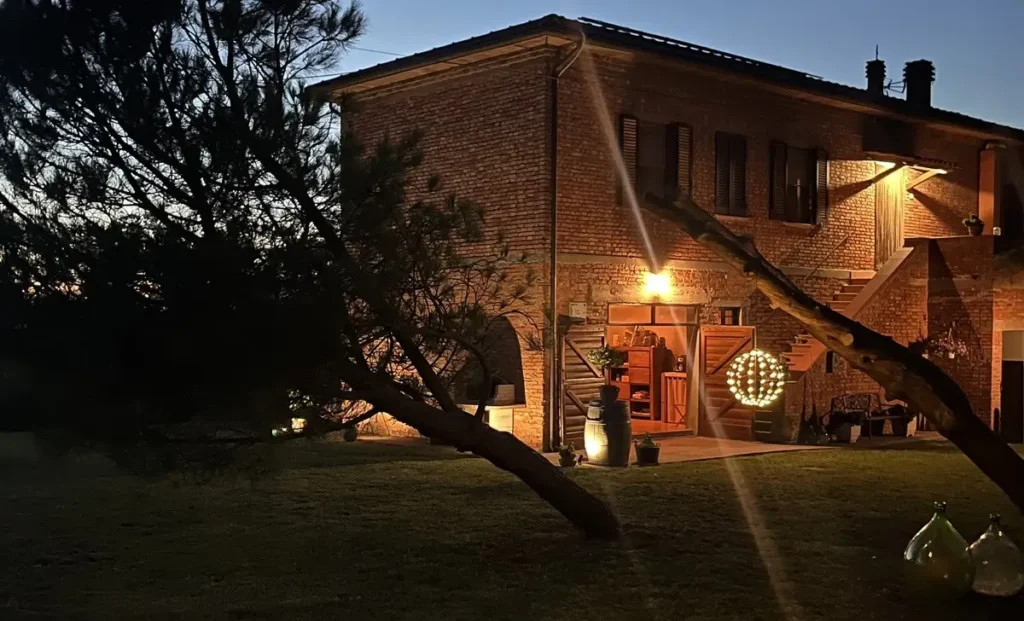 Toscaanse bakstenen boerderij bij avondschemering, met verlichte veranda