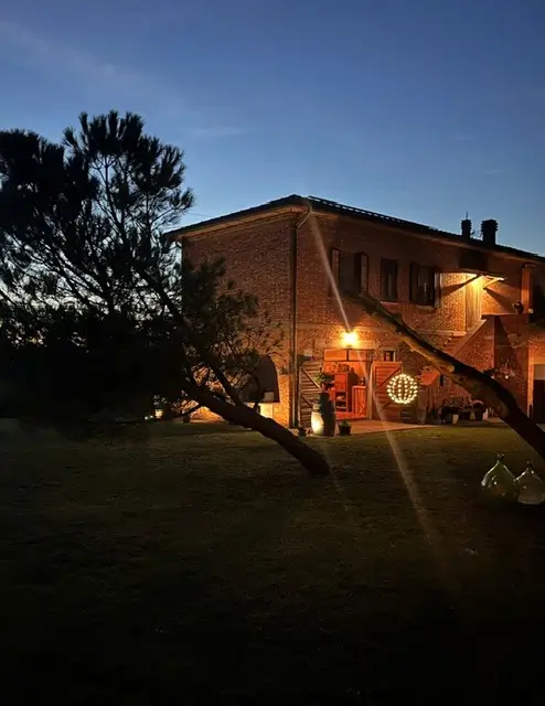 Toscaanse bakstenen boerderij bij avondschemering, met verlichte veranda