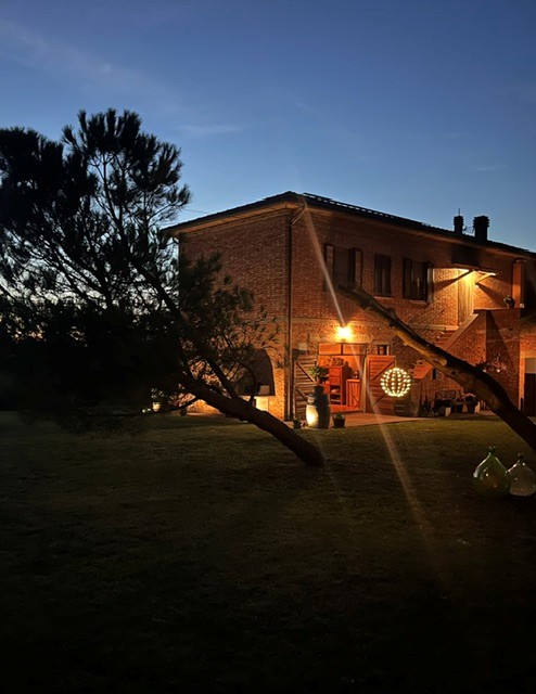 Toscaanse bakstenen boerderij bij avondschemering, met verlichte veranda